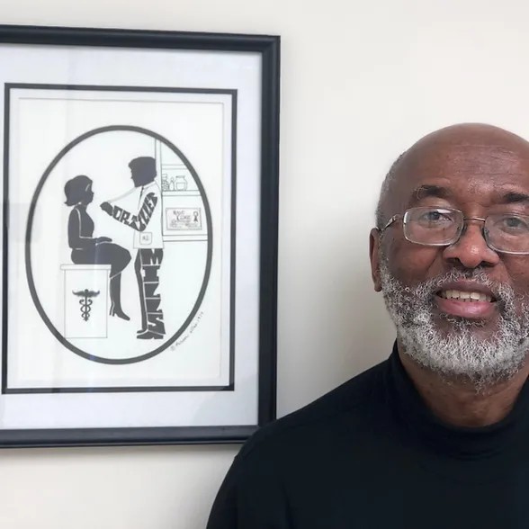 Portrait of a person beside a framed silhouette artwork.