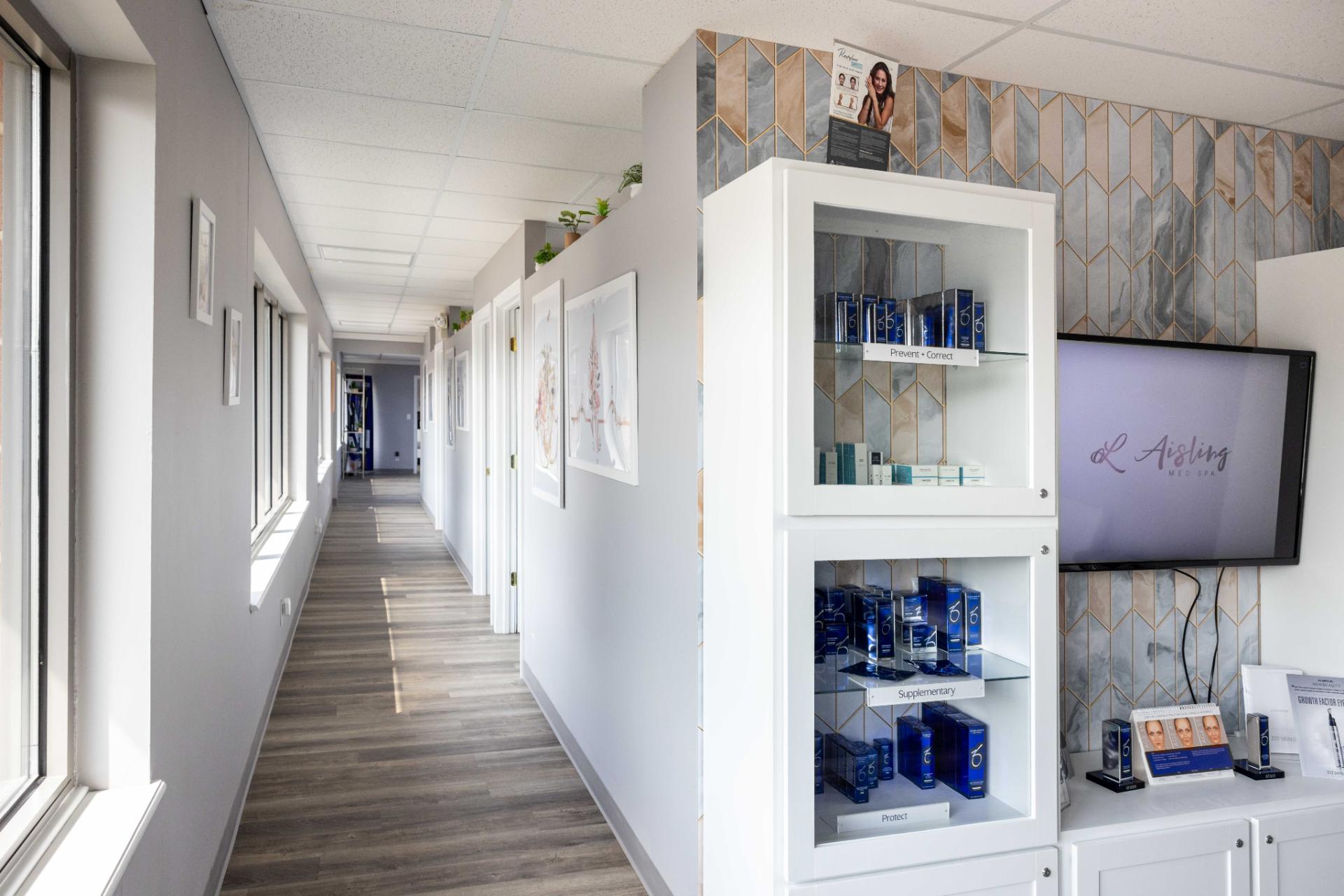 Spa hallway with skincare display and branded TV screen.