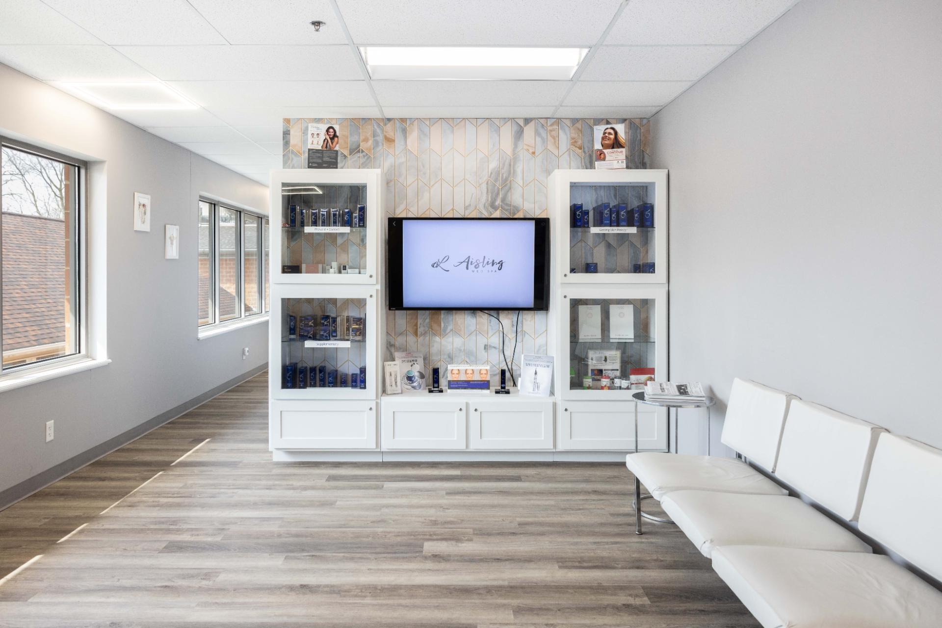 Modern waiting room with white seating and skincare products display.