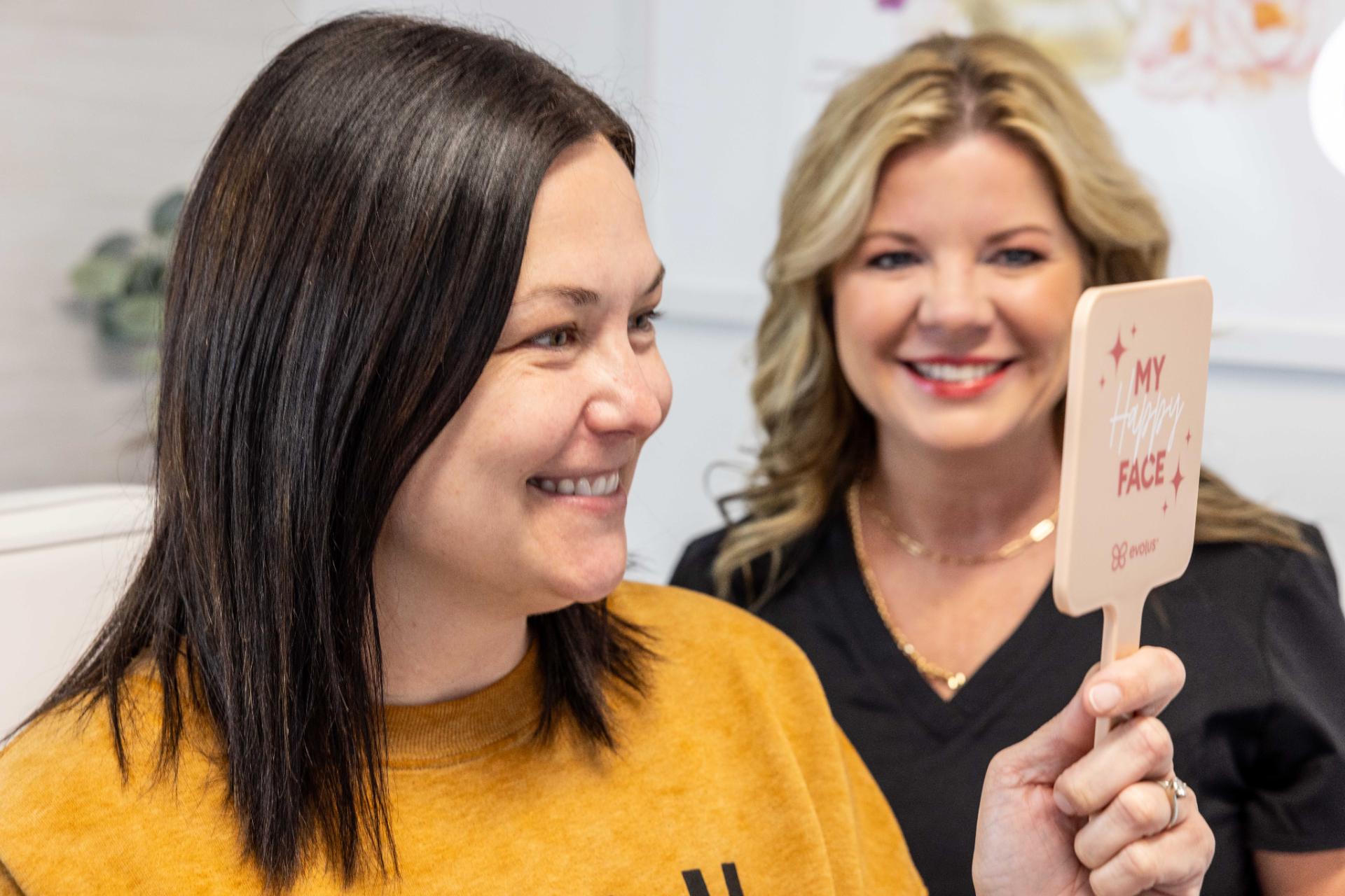 Woman smiling, holding a My Happy Face mirror.