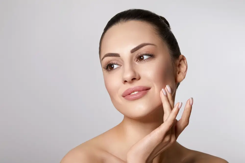 Woman with clear skin gently touching face.