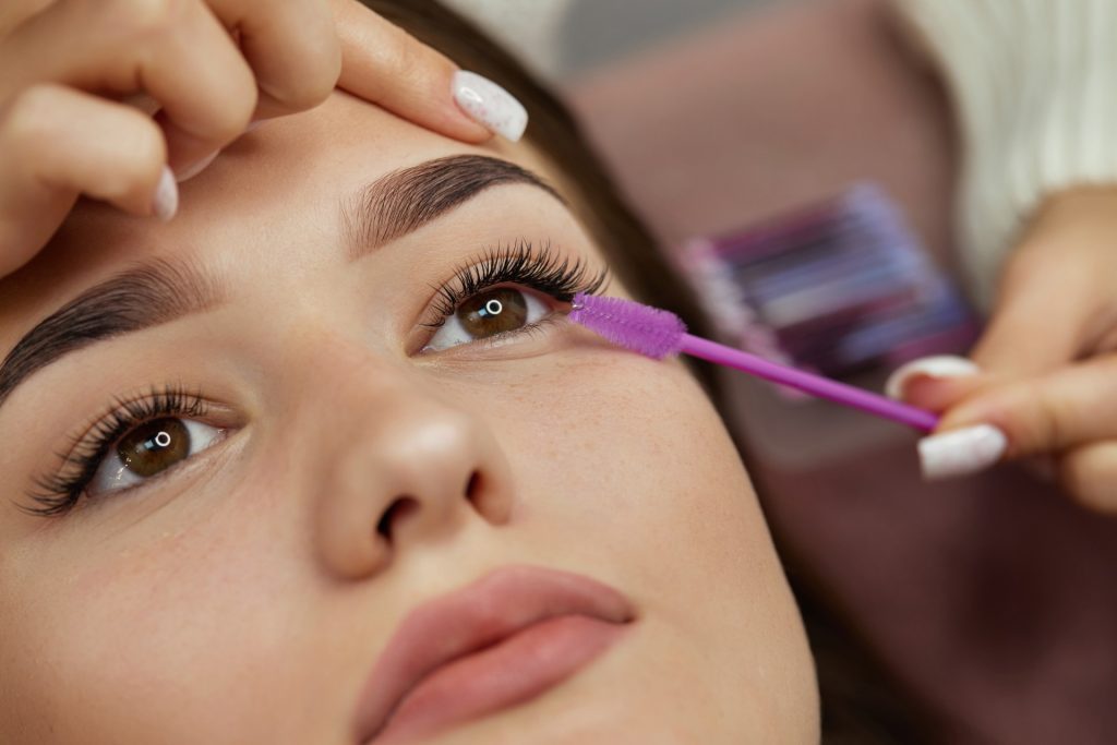 Eyelash application with a purple wand on woman's eye.