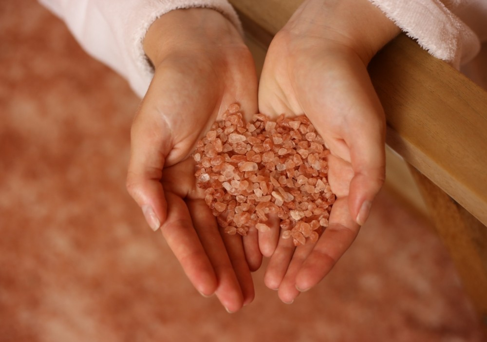 Hands holding pink Himalayan salt crystals.
