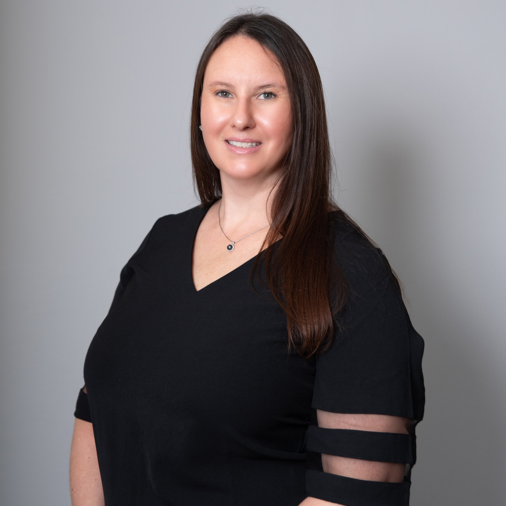 Woman with long hair wearing a black top, smiling.